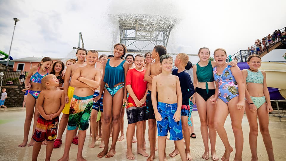 Group of young people in bathing suits anxiously awaiting the Soak Zone's dumping bucket as water falls above them